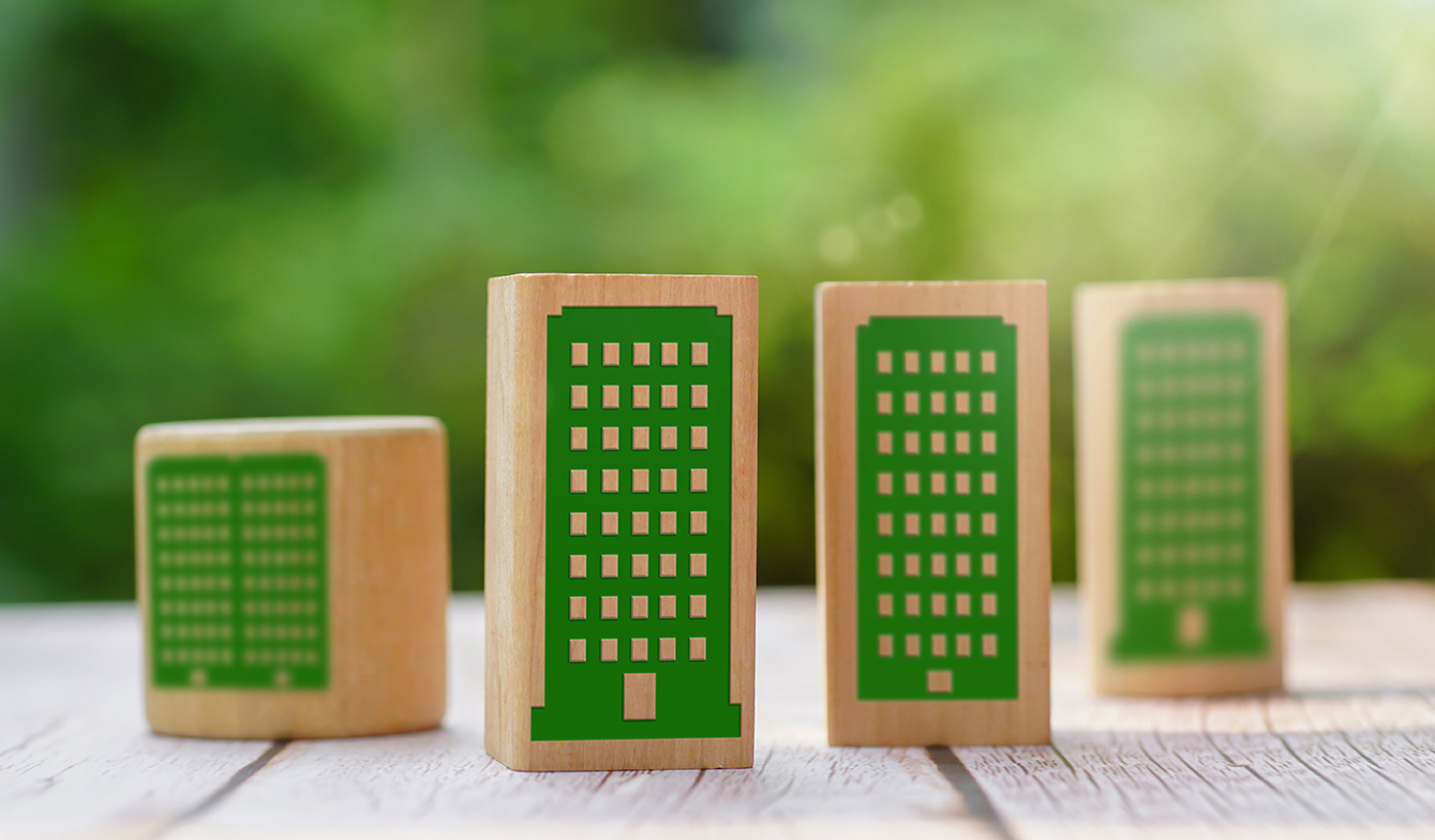 Green building symbols on wooden cubes on a wood table and natur